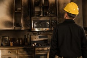 Disaster restoration crew member inspecting fire damage in kitchen